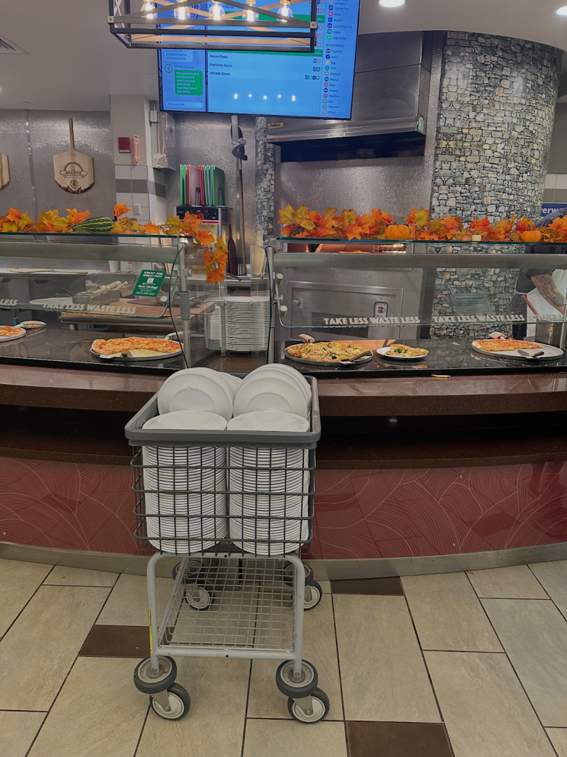 tables with pizza and plates in front of it with an oven behind.