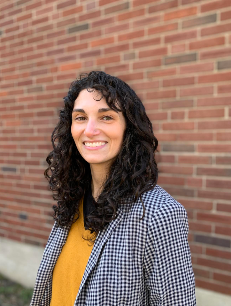 a woman stands in front of a brick wall