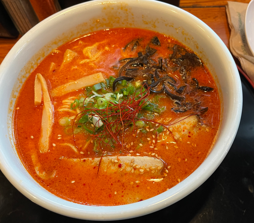 An image of ramen with orange soup