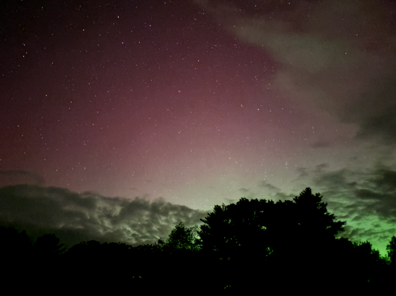 Pink sky with a hint of green, on an open plain, dappled by shimmering stars. 