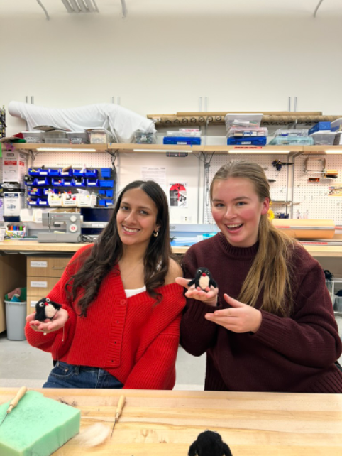 two girls in the Makerspace holding their finished needle felted penguins