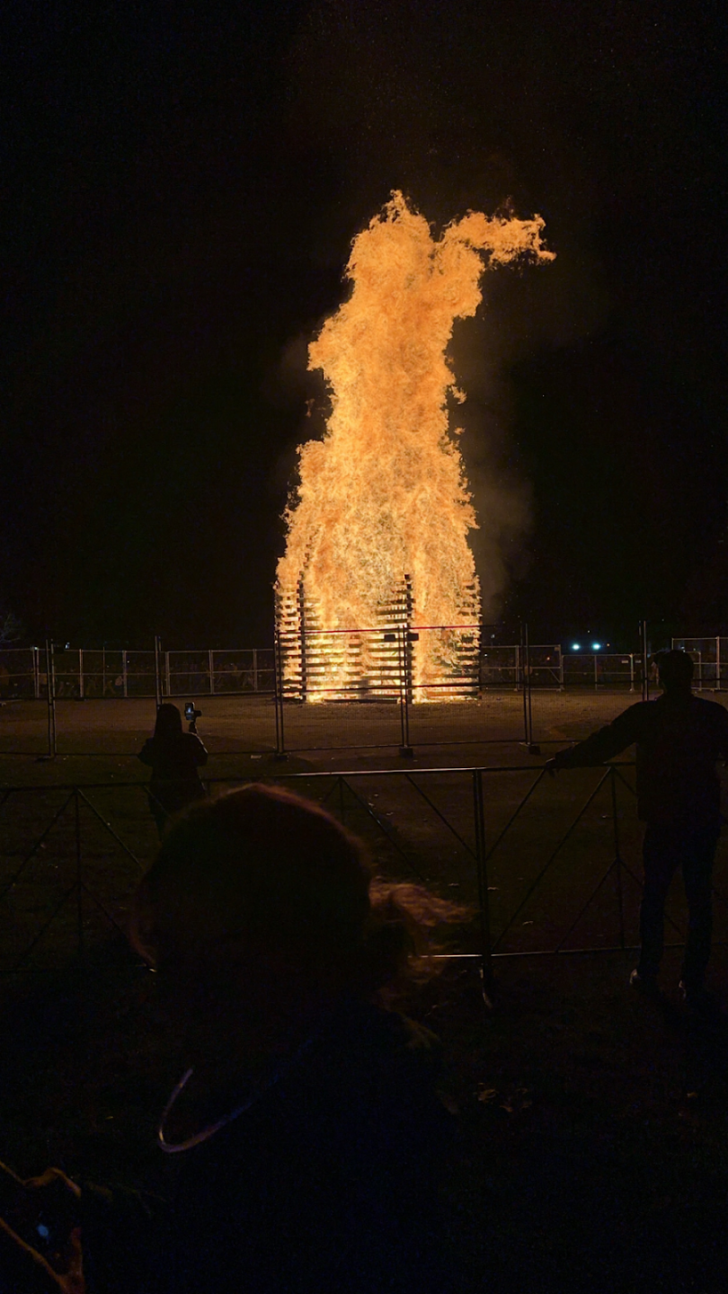 A huge fire surrounded by metal fencing.