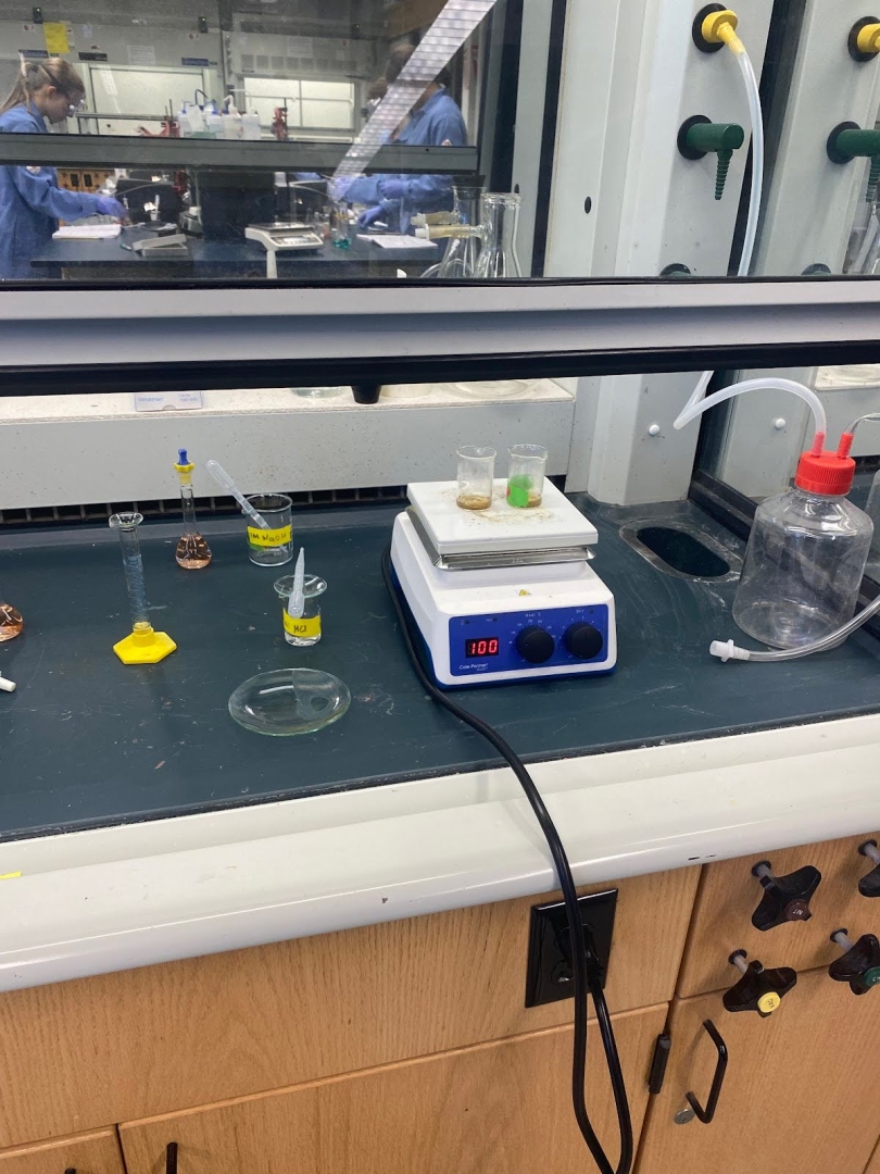 A laboratory setup with a heating plate, beakers and flasks containing different coloured solutions.