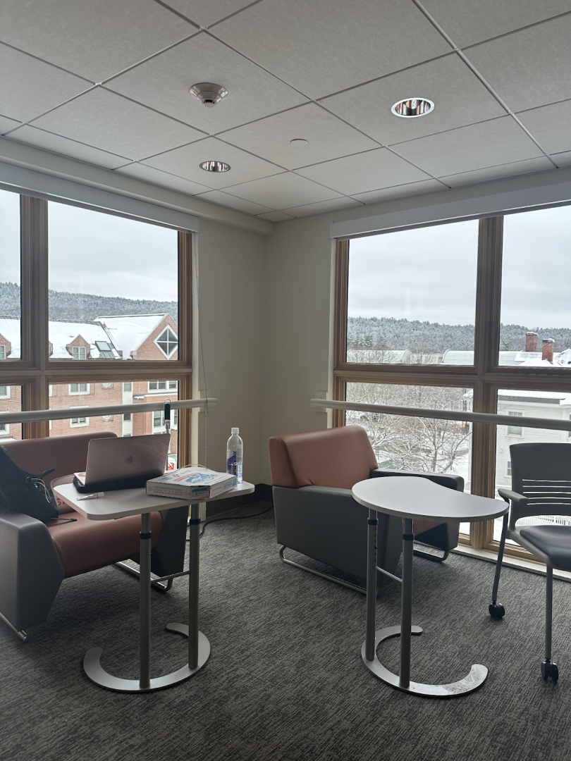 A study room with two large windows and two lounge chairs with small tables in front of them. 