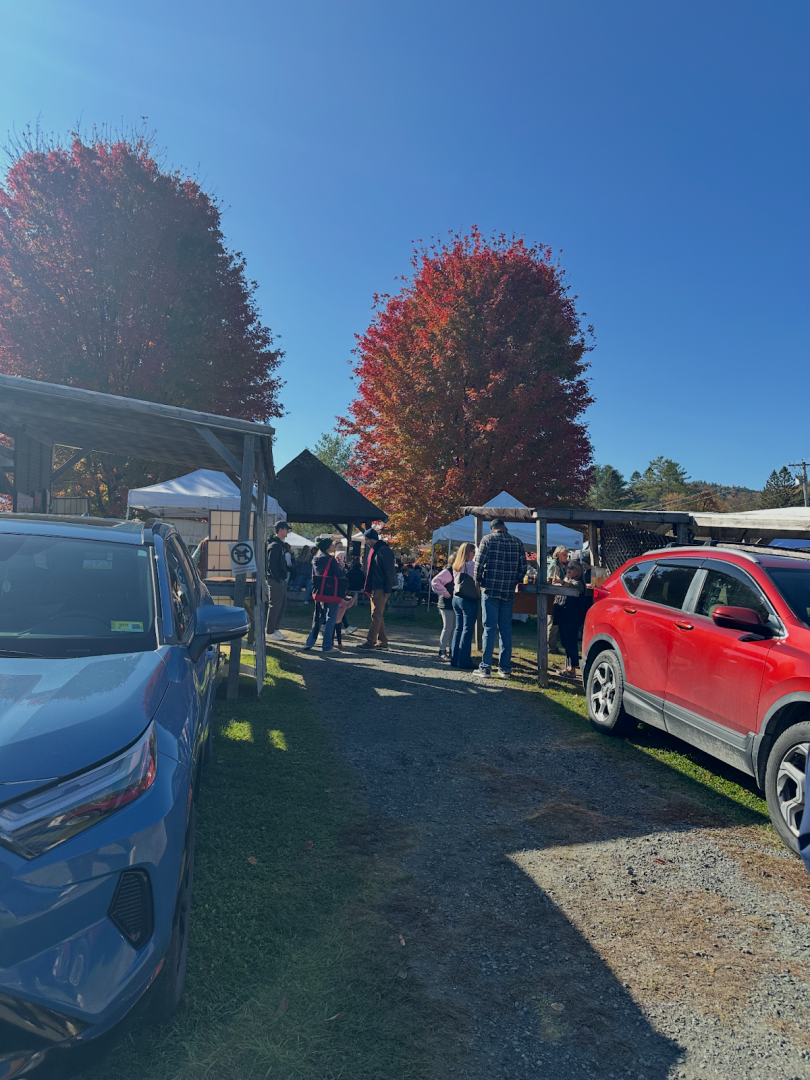 Entrance to tents with cars and two trees with red and orange leaves.