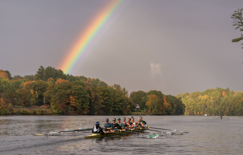 a rowing boat on a river with a rainbow