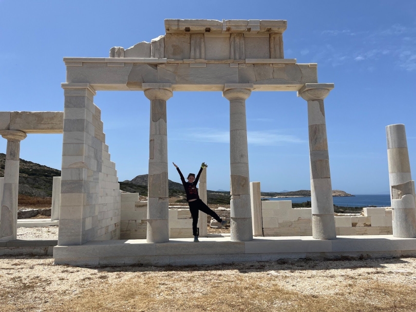 A woman stands with her arms out on a marble building