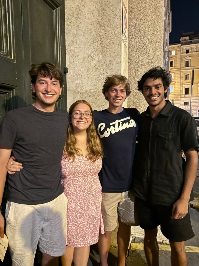 A photo of me, Lauren, with my friends Matt, Witt, and Asfand on our last night in Rome. We are standing close to each other and smiling widely at the camera.