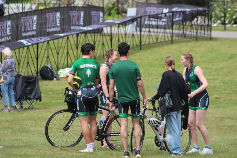 A group of Dartmouth triathletes standing in a circle in discussion next to the race finish line.