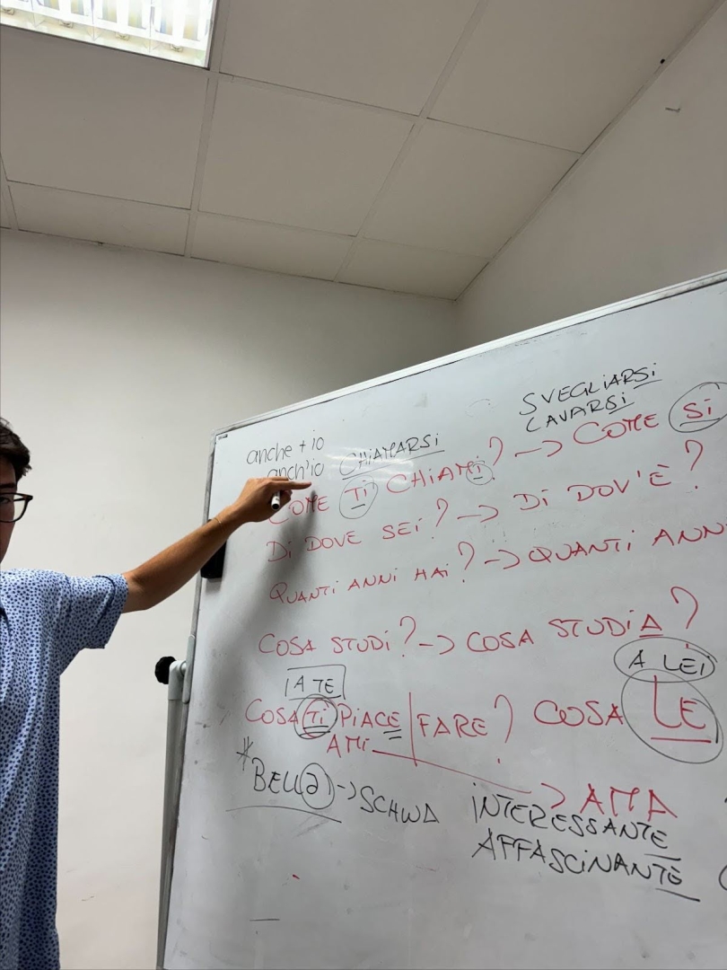 A person pointing to Italian phrases on a whiteboard