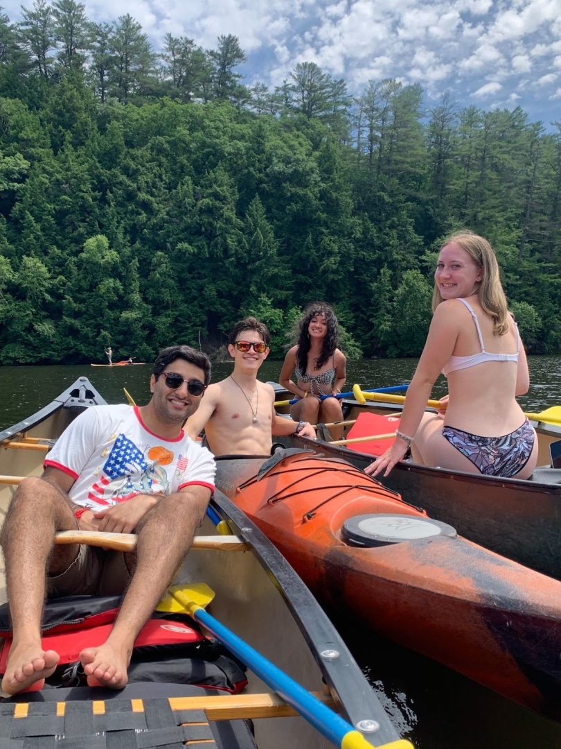 Four people smiling in canoes and kayaks on the Connecticut River.