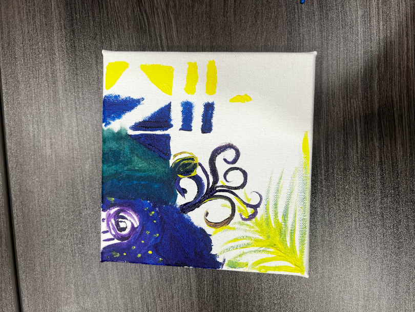 a half-filled canvas of yellow, blue, and purple paint 