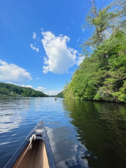 Photo from a canoe of Gabriel and Azariah in the distance on another canoe, paddling on the Connecticut River.