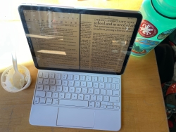 A photo of an iPad on a table with some arroz con leche in a plastic container to the left of it and a green water bottle to the right of it