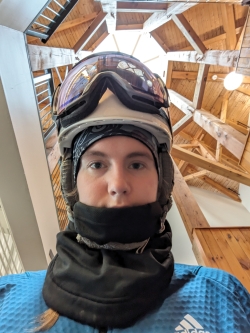 Lily with ski gear on in the center atrium of skodj, surrounded by wood beams and skylights at the top.