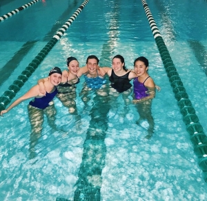 Abbi in center, surrounded by 4 friends standing in the pool after practice