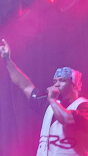A photo of A$AP Ferg singing on stage, holding up his right hand