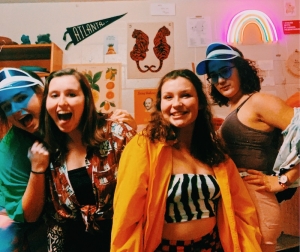 Abbi and 3 friends posing in very colorful attire in a dorm room