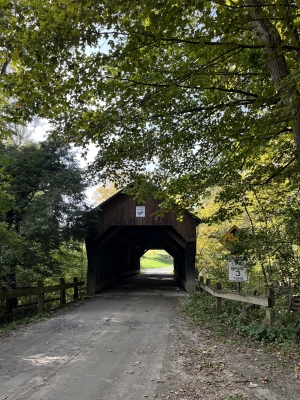 A photo of a wooden covered bridge near Hanover. The bridge is surrounded by fall foliage.