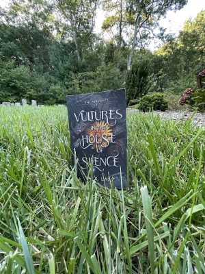 a picture of Abdul R. Latif's book Vultures in the House of Silence standing in the grass with green trees behind it