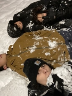 A picture of me and my friends laying on the snow. 