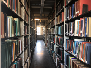 A narrow aisle of Dartmouth library stacks, filled with books on both sides