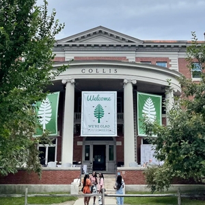 A photo of people standing in front of Collis Center, which has Welcome Home banners up between columns