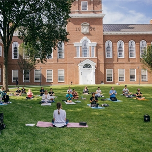A photo of students doing yoga on the lawn in front of Baker Library
