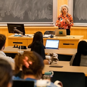 A photo of a professor talking during a class to a room of students