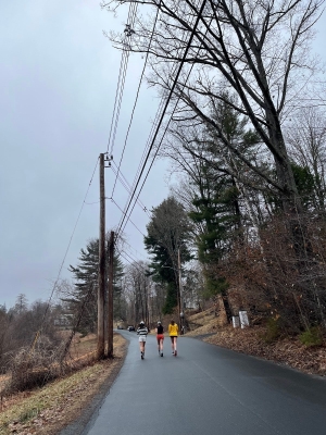 a cloudy day. Serena's friends are running on the pavement in front of her. 