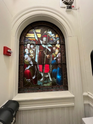 a stained glass window surrounded by a white wall.