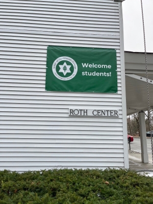 A white building with a green banner that says welcome students.