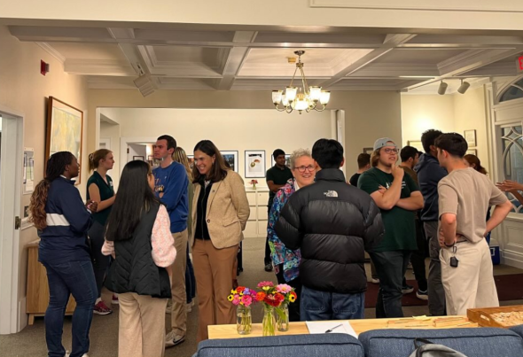 There are many people inside a small inside space at night. This is a picture in the main entry way of the Tucker Center where the Tucker Ambassador Council did concentric circle greeting exercises.
