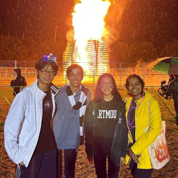 Group photo of people standing in front of a large bonfire