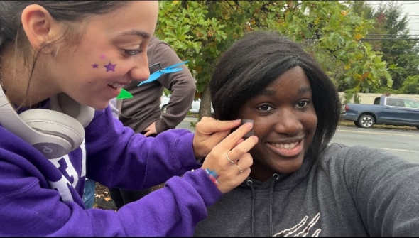 A picture of a volunteer putting face paint on another volunteer.