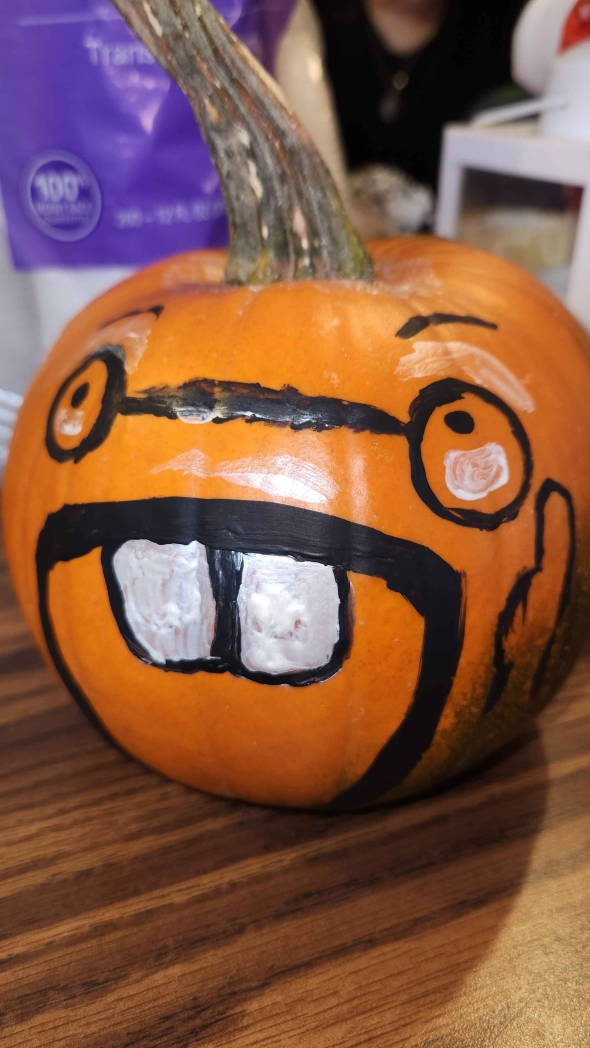A photo of a pumpkin with glasses and a wide open mouth with 2 teeth.