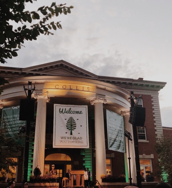 Collis Center at dusk with a sign reading "Welcome! We're glad you're here!"