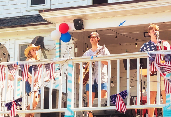 A photograph of 3 people in a band performing at a balcony.