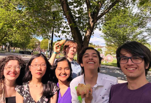 A photo of 6 people smiling in front of the camera against a background of a tree.