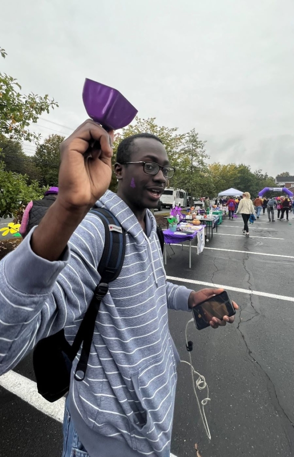A picture of a student volunteer waving a purple bell.