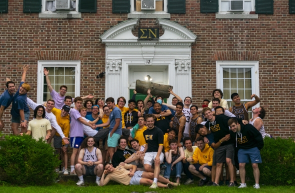 group of friends posing in front of fraternity 