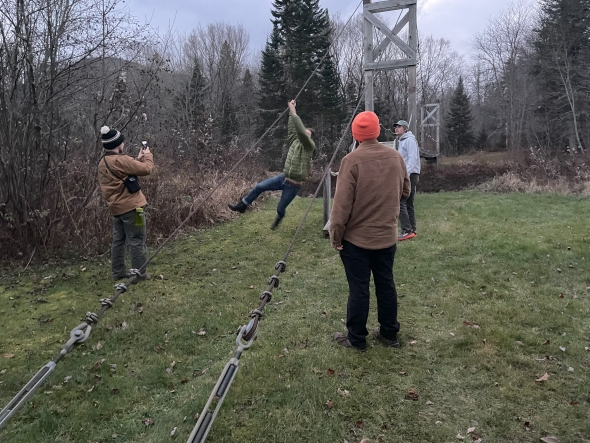 several people stand by while Jack is swinging off the line of a bridge