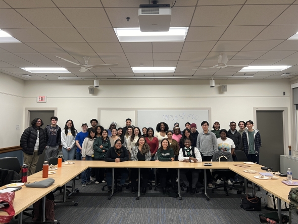 Members of the Dartmouth Minority Pre-Law Association pose proudly behind four alumni panelists in a well-lit conference room.
