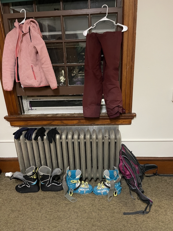 a picture of Kalina's skiing gear drying at her room - ski pants hang from the wall, ski boots dry by the heater