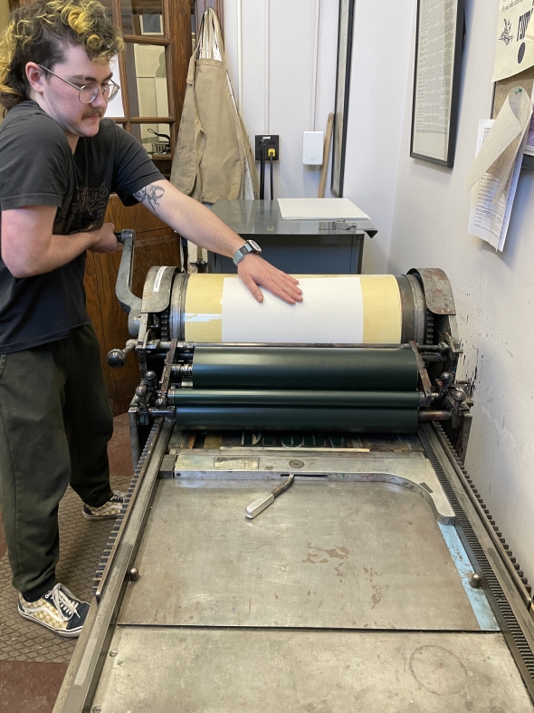 a picture of Farrar, a Flora and Fauna leader, printing the first FnF poster in the Book Arts Center