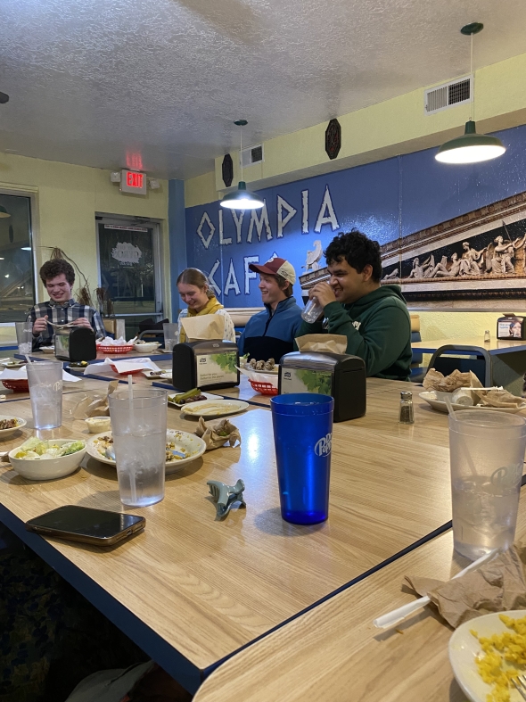  Dinner at a cafe with a blue and cream colored wall behind four of the Dartmouth students who are laughing in the picture. 