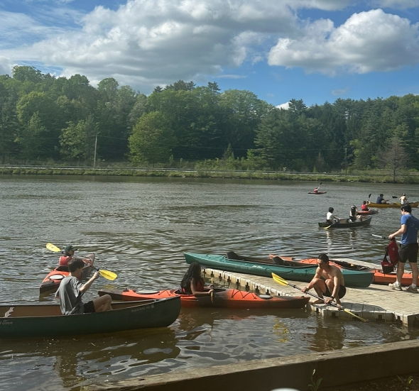 The Connecticut River is bustling with activity, many people kayaking and canoeing as they approach the boat dock.