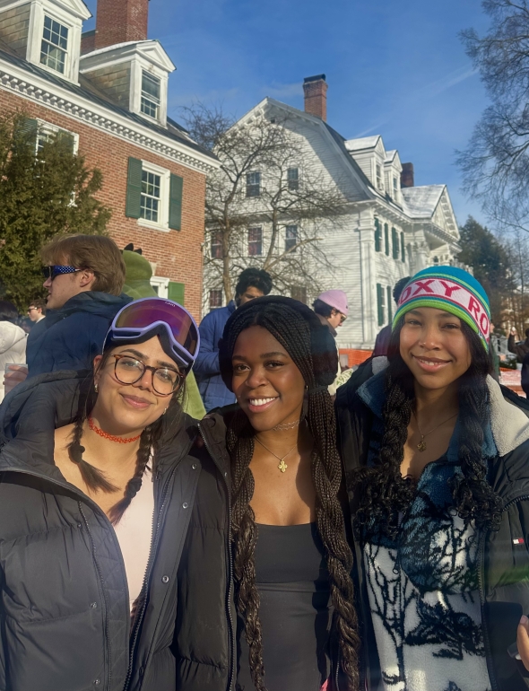 Three girls are layered in winter-clothing, beaming at the camera.
