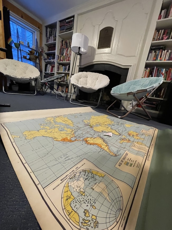 a picture of a map, lying on the library floor, with chairs and books at the back