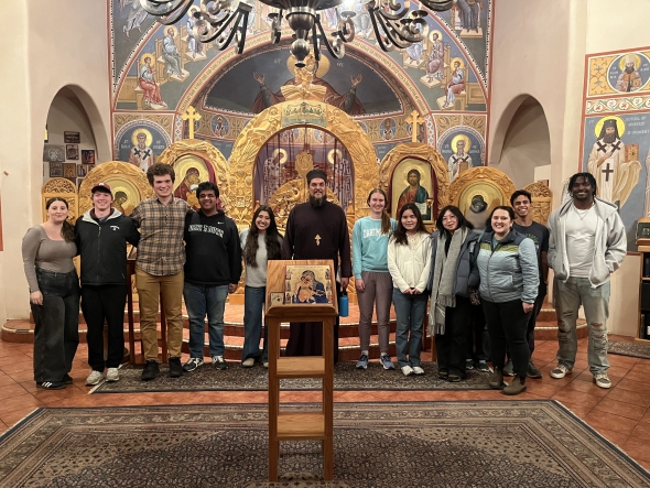This photo is inside the main part of the Holy Trinity Orthodox Church, where services take place. There is a chandelier at the top of the photo and ornate iconography on the walls.
